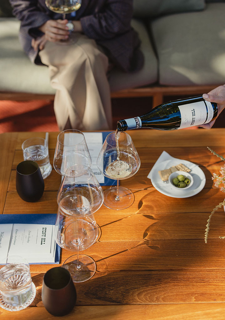 A tasting at Stony Hill with wine being poured into a wine glass at a table with guests.