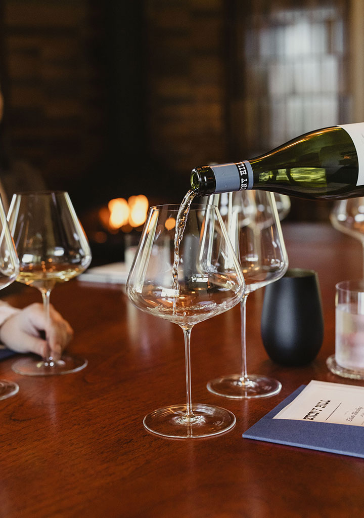 A bottle of Stony Hill Chardonnay wine being poured into a glass for a tasting at The Residence.