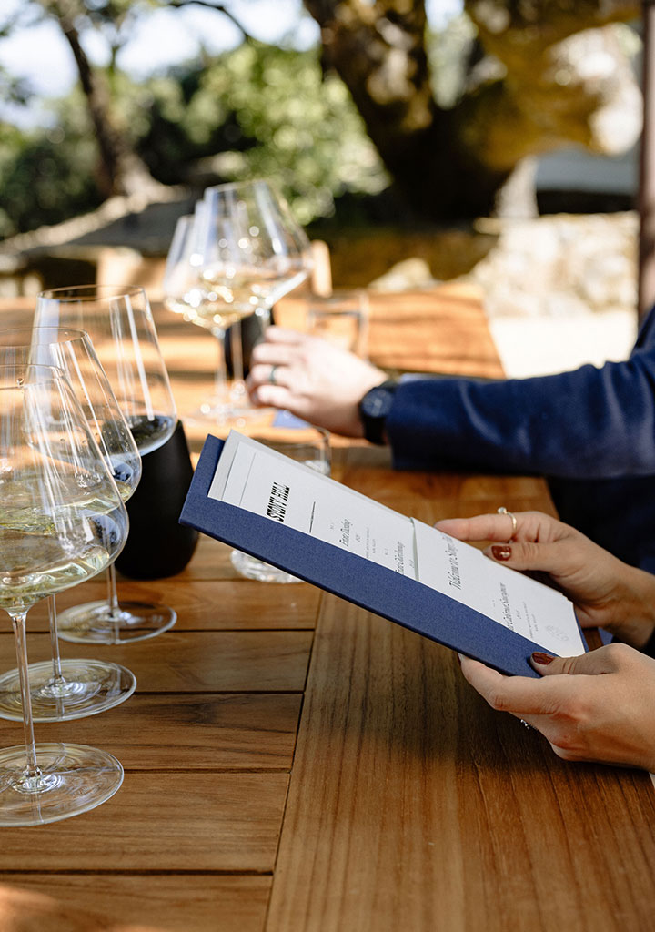 A tasting at Stony Hill with wine being poured into a wine glass at a table with guests.