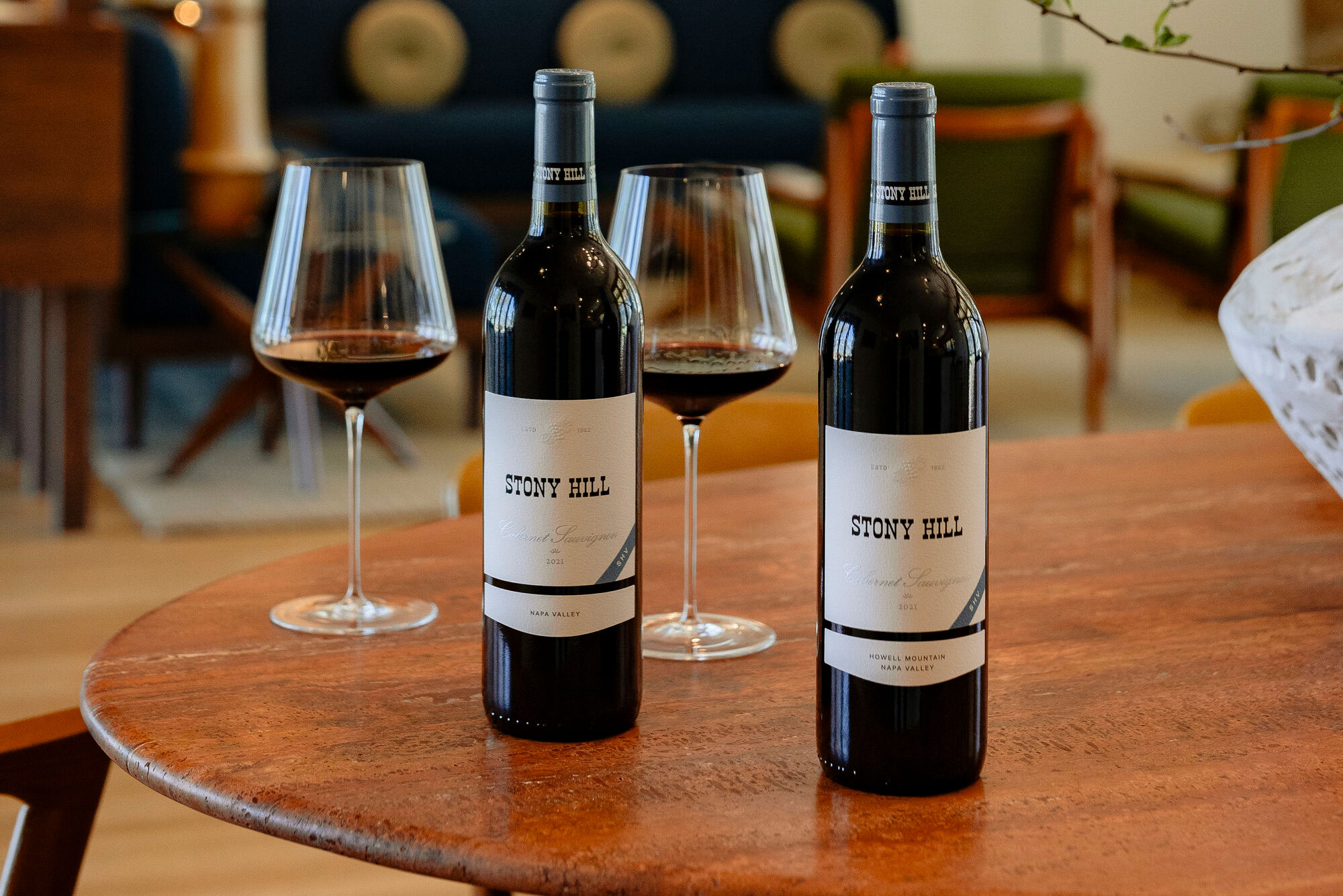 A bottle of Stony Hill Linda Falls Cabernet Sauvignon and Ink Grade Cabernet Sauvignon on a table next to two glasses filled with wine.
